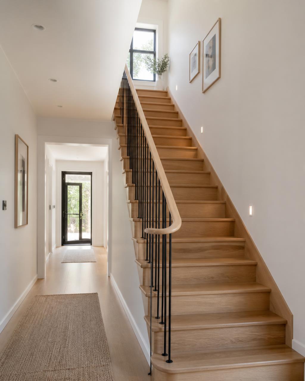 Oak staircase with slim dark balustrade in a bright hallway